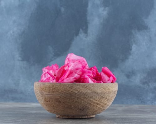 Wooden bowl full with canned pink cabbage on grey background. High quality photo